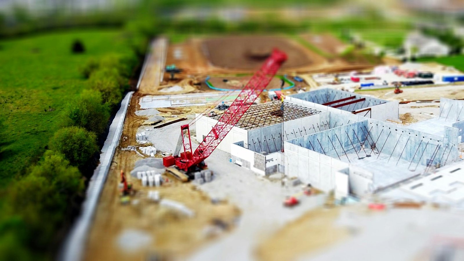 Área de ingeniería civil, zona en construcción. Destaca un edificio de gran tamaño en sus
primeras etapas de construcción, con estructuras de concreto sin terminar y una grúa roja
que se alza sobre el sitio. El edificio se encuentra en un área extensa, rodeada de tierra sin
pavimentar y montones de materiales de construcción