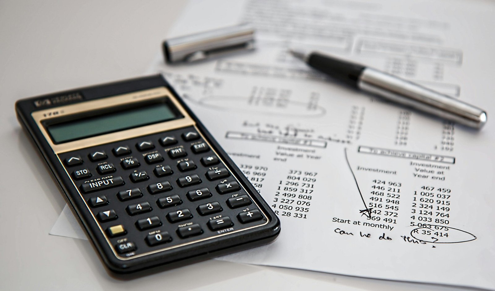 Calculadora encima de una hoja de papel con cálculos matemáticos y diagramas, y un bolígrafo,
todos sobre una superficie plana. Los elementos sugieren que se está realizando trabajo
matemático o tareas.