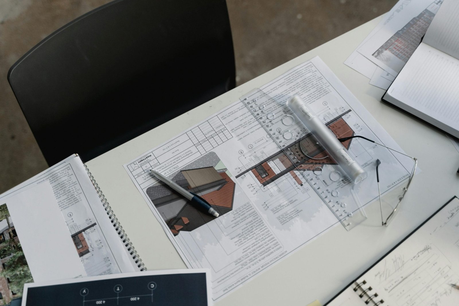 Plano arquitectónico sobre una superficie plana. El plano está compuesto por líneas finas y
símbolos que representan las diferentes partes de un edificio, como paredes, puertas,
ventanas y habitaciones. Se pueden apreciar números y medidas en el plano, lo que indica
las dimensiones de las diferentes áreas. Junto al plano, hay una regla y un bolígrafo
instrumentos utilizados para tomar medidas o realizar anotaciones.